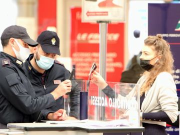 Agentes de las fuerzas del orden realizan controles a los pasajeros en la estación central de ferrocarril de Milán, Italia, el 2 de abril de 2021