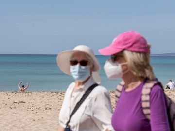 Dos turistas caminan por el paseo marítimo de la playa de Palma de Mallorca