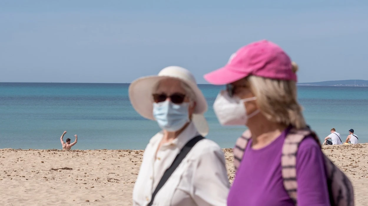 Dos turistas caminan por el paseo marítimo de la playa de Palma de Mallorca Dos turistas caminan por el paseo marítimo de la playa de Palma de Mallorca