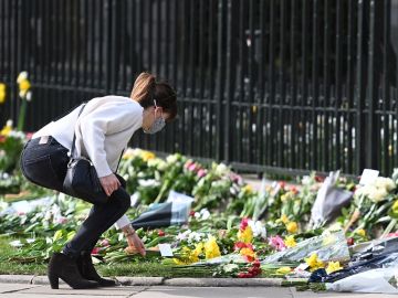 Una mujer deposita una ramo de flores frente al Castillo de Windsor tras la muerte del Duque de Edimburgo