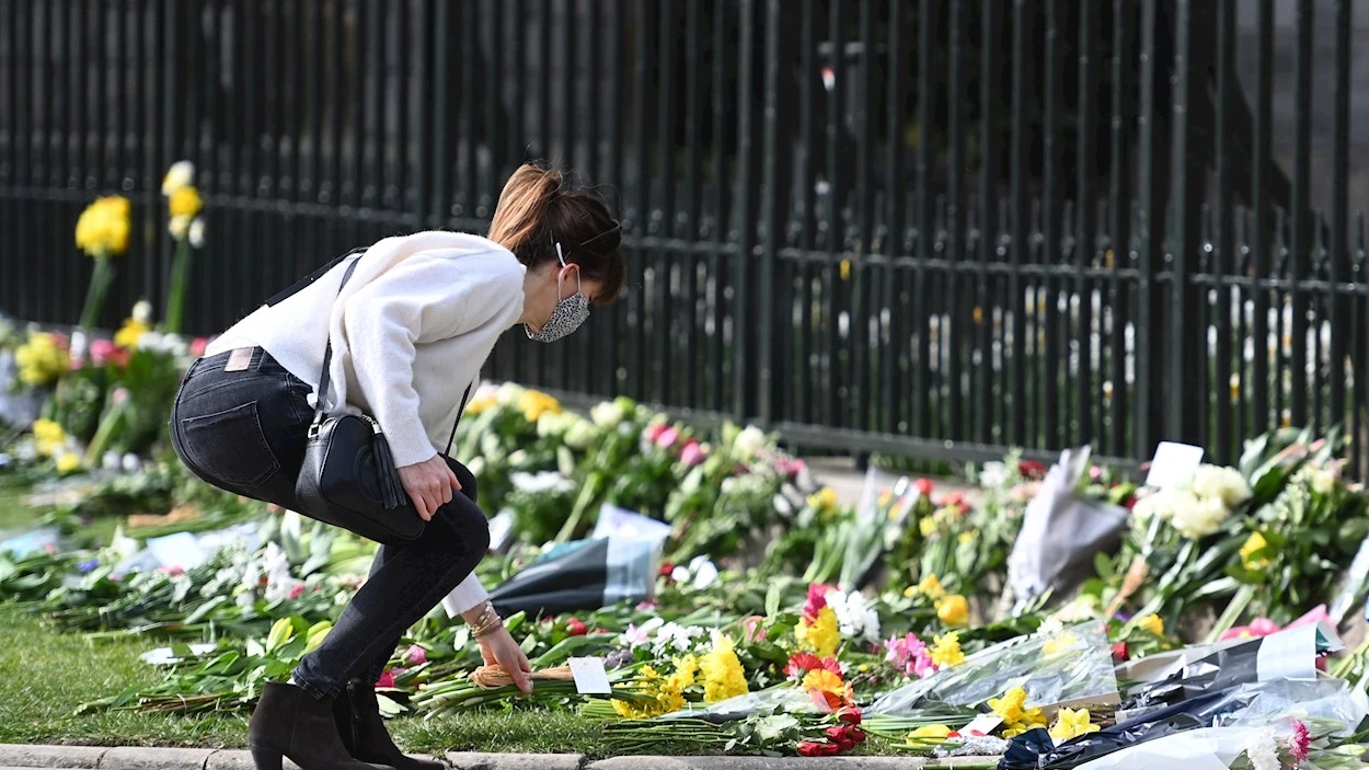 Una mujer deposita una ramo de flores frente al Castillo de Windsor tras la muerte del Duque de Edimburgo