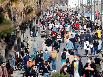 Decenas de personas pasean por el paseo maritimo de playa de la Malvarrosa, en Valencia