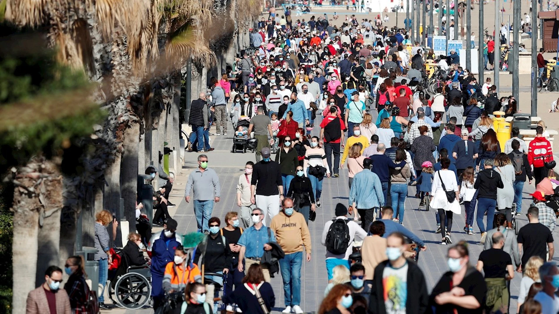 Decenas de personas pasean por el paseo maritimo de playa de la Malvarrosa, en Valencia