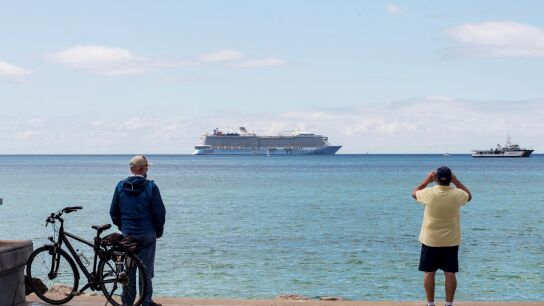Unos hombres observan un crucero tur&iacute;stico en la bah&iacute;a de Palma de Mallorca