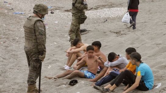 Miembros del Ej&eacute;rcito de Tierra vigilan a un grupo de inmigrantes menores tras su entrada en Ceuta