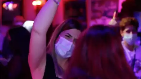 Una joven con mascarilla en un local de ocio nocturno Una joven con mascarilla en un local de ocio nocturno