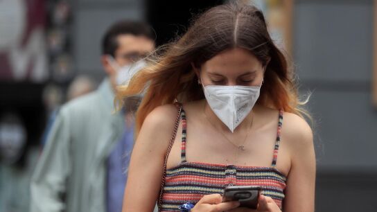 Una joven con mascarilla camina por Madrid