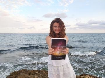 María Cuadrado sostiene su primer libro, 'Beyond', en la playa