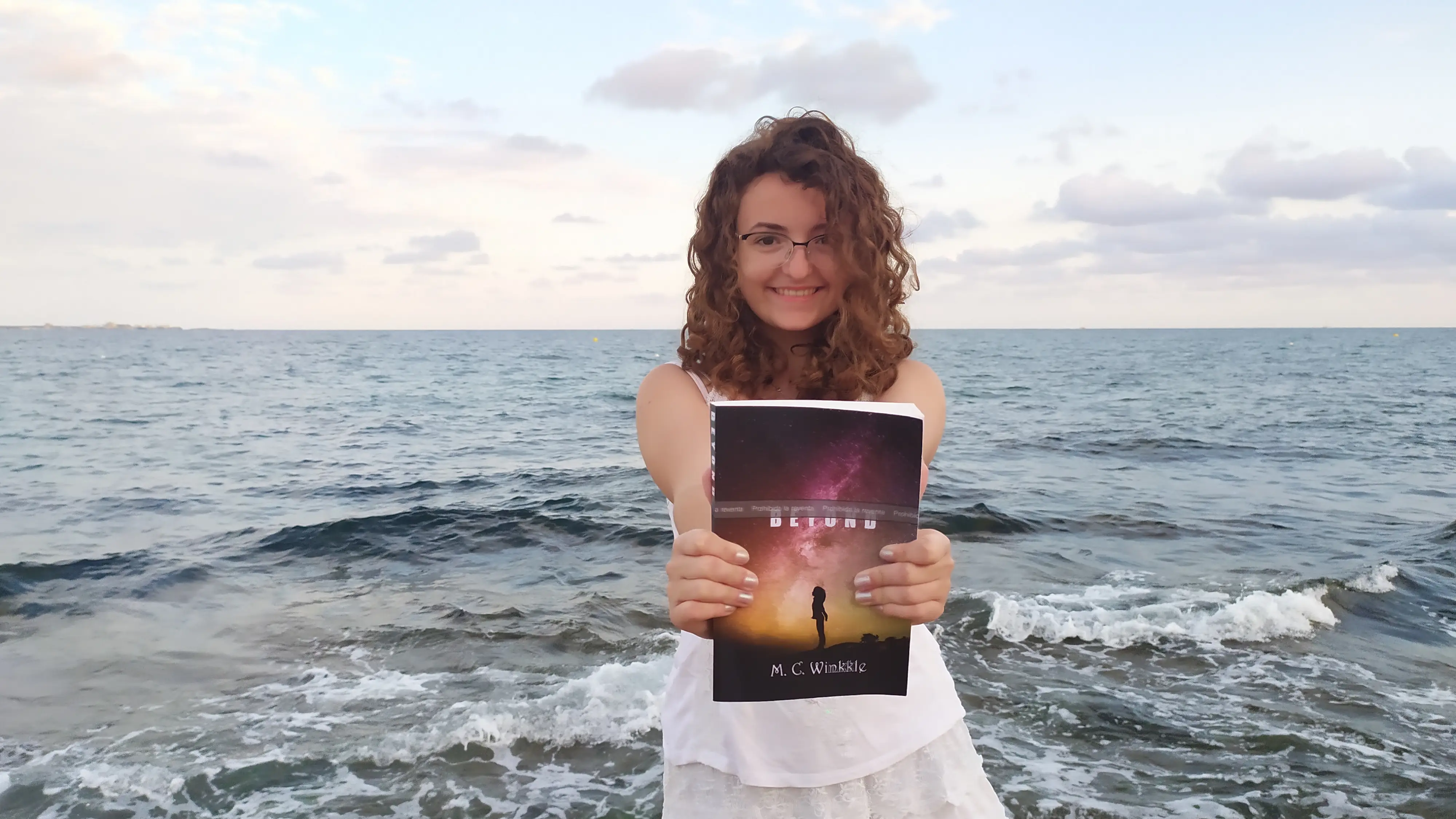 Mar&iacute;a Cuadrado sostiene su primer libro, 'Beyond', en la playa