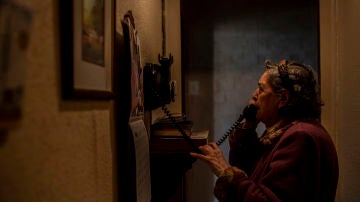 María intenta llamar a su prima de Zaragoza, la única familiar que le queda con vida. Su prima insiste en que vaya con ella, pero María responde que no se irá hasta que vuelva a ver a José, su amigo y compañero de piso, ingresado por Covid-19 en un centro sanitario de Barcelona, Cataluña, 15 de abril, 2020. (© Nuria Prieto)