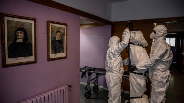 "Trabajadores de la empresa de servicios funerarios Mémora retiran el cuerpo de Teodora Ros Plana, sor Ros, de 103 años, fallecida por covid-19 en el convento Llar Verge de Gracia. Barcelona, 5 de octubre, 2020. Esta foto forma parte del reportaje: Éxitus (© Àngel García)"