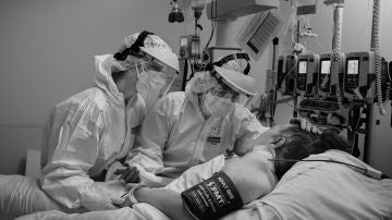 La Doctora Inés Lipperheide y la enferma Gema Martín intentan convencer a una paciente Covid de la UCI del Hospital de Puerta de Hierro que siga luchando por su vida, aunque no albergan muchas esperanzas de que puedan salvarle. La amenaza de una tercera ola de la pandemia, a medida que se acercan las navidades y junto a la aparición de la nueva cepa del virus de la Covid-19 en Reino Unido, mantiene en vilo a la comunidad médica. Se estima que la pandemia ha causado en España más de 70.000 fallecidos,​ de los cuales más de 50.000 han sido confirmados mediante la prueba de PCR. La gran mayoría eran personas mayores de 65 años.​ Según un estudio de seroprevalencia el 5% de la población española había sido infectada por el virus hasta junio. Madrid, 21 de Diciembre 2020. (© Álvaro Ybarra Zavala)