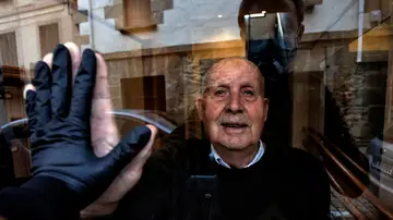 Visita a mi abuelo Miguel, de 90 años, durante el confinamiento que saluda a través del cristal del portal. El alto índice de personas mayores afectadas por la Covid-19 les obligó a un estricto aislamiento con la esperanza de evitar el contagio. Huarte, Navarra, 1 de abril, 2020. (© Unai Beroiz)