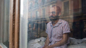 Joan sentado en la cama tras despertarse en Barcelona. Son meses en los que pensamos mucho sobre lo que estamos viviendo. De hecho, los dos hemos cogido la costumbre de trasladar lo que vivimos en nuestros diarios personales. Por ejemplo, Joan, escribe el 23 de marzo: “Comienza una nueva semana de confinamiento que cada vez se hace más complicado. Wayra ha salido a la calle a comprar y, como cada vez, vuelve preocupada por la posibilidad de haber traído el maldito virus a casa. Mantener la calma en un momento sin certidumbres ni seguridades es muy complicado, y nos puede llevar a caer en la tentación de la preocupación excesiva.” Barcelona, 30 de mayo, 2020. (© Pablo García Sacristán)