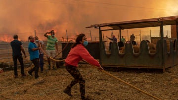 Una mujer ayuda en las tareas de extinción de un incendio cerca de una nave ganadera en Vegalatrave. Zamora, 15 de agosto de 2020. (© Emilio Fraile)
