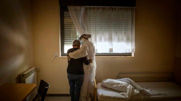 Una anciana y una trabajadora se abrazan en la habitación en la que la primera permanece confinada, en una residencia de la provincia de Barcelona, España, 29 de abril, 2020. (© Santi Palacios)