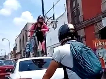 Una ciclista pasa con su bici por encima de un coche que estaba aparcado en un carril bici Una ciclista pasa con su bici por encima de un coche que estaba aparcado en un carril bici