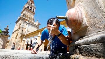 Joven se refresca en una fuente de Córdoba