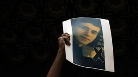 Un joven levanta una foto de Samuel Un joven levanta una foto de Samuel