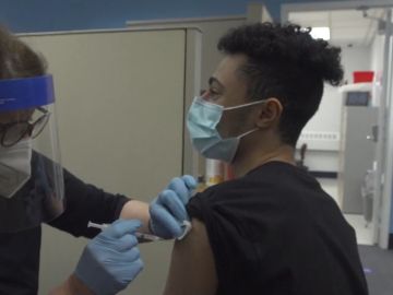 Una sanitaria administra una vacuna contra el coronavirus a un joven