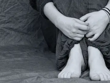 Una niña sentada abrazándose las rodillas Una niña sentada abrazándose las rodillas