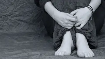 Una niña sentada abrazándose las rodillas