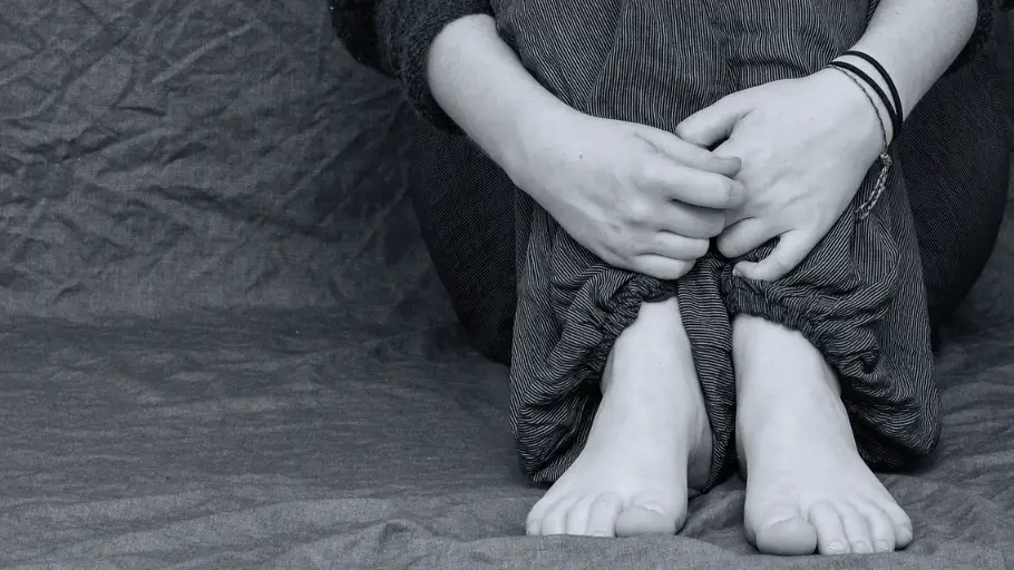 Una ni&ntilde;a sentada abraz&aacute;ndose las rodillas