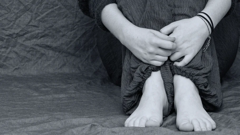 Una niña sentada abrazándose las rodillas Una niña sentada abrazándose las rodillas