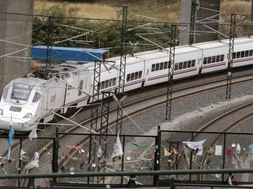 Un tren alvia similar al accidentado en Angrois, pasa por la curva donde permanecen objetos colocados en memoria de las víctimas mortales