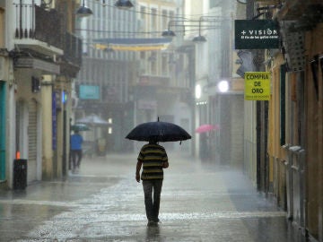 Un hombre camina, este lunes, bajo una intensa lluvia por el centro de la ciudad de Gandía.