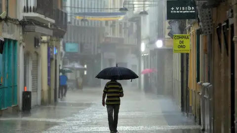 Un hombre camina, este lunes, bajo una intensa lluvia por el centro de la ciudad de Gandía. Un hombre camina, este lunes, bajo una intensa lluvia por el centro de la ciudad de Gandía.