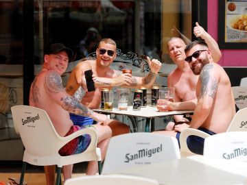 Un grupo de hombres saludan sentados en una terraza de Benidorm. 