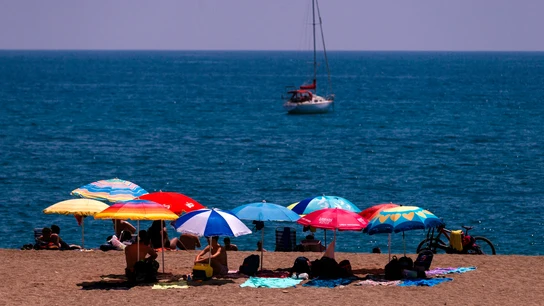 Unos bañistas se protegen del sol bajo las sombrillas en la playa de La Malagueta Unos bañistas se protegen del sol bajo las sombrillas en la playa de La Malagueta
