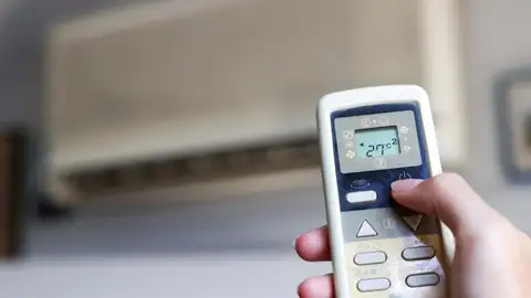 Una persona encendiendo el aire acondicionado Las maneras de refrescar la casa sin necesidad de utilizar el aire acondicionado