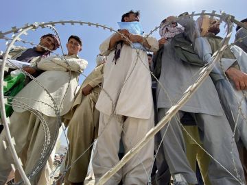 Un grupo de afganos, algunos de los cuales extrabajadores de la OTAN, Unión Europea y ONU, esperan en las afueras del aeropuerto Hamid Karzai de Kabul para intentar abandonar el país tras la llegada de los talibanes