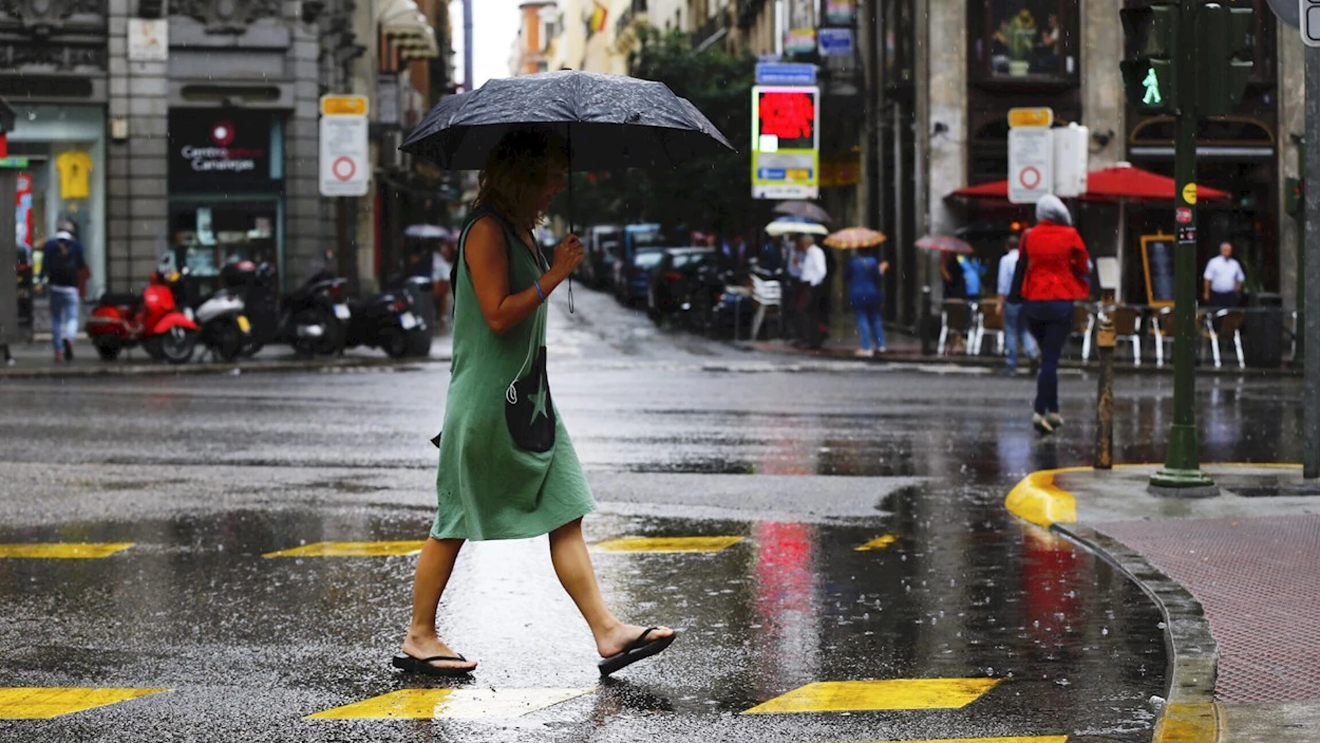 Una mujer se protege de la lluvia en el centro de Madrid.