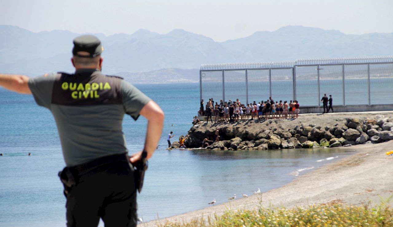 Un agente de la Guardia Civil observa a inmigrantes marroquíes llegados a nado a Ceuta