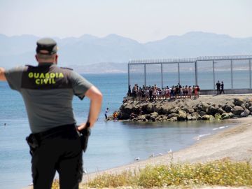 Un agente de la Guardia Civil observa a inmigrantes marroquíes llegados a nado a Ceuta