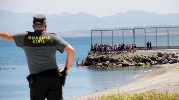 Un agente de la Guardia Civil observa a inmigrantes marroqu&iacute;es llegados a nado a Ceuta