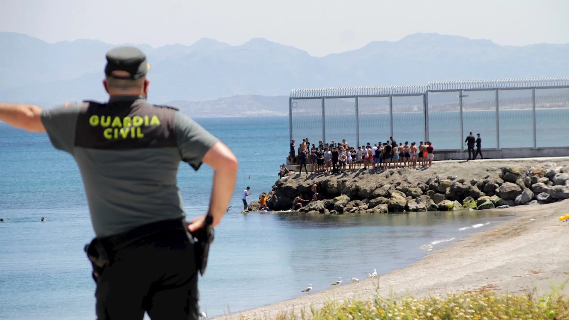 Un agente de la Guardia Civil observa a inmigrantes marroquíes llegados a nado a Ceuta Un agente de la Guardia Civil observa a inmigrantes marroquíes llegados a nado a Ceuta