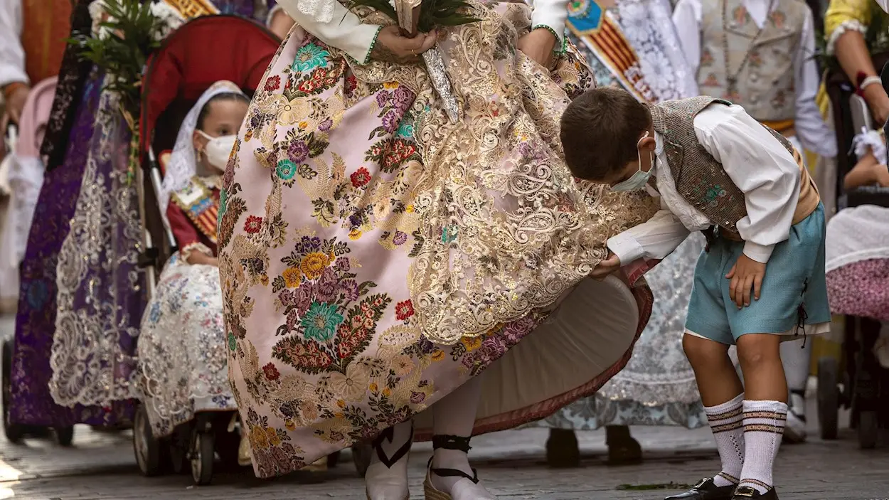 Un ni&ntilde;o observa un traje tradicional de fallera durante la Ofrenda a la Virgen, uno de los actos m&aacute;s emotivos de las Fallas, mucho menos multitudinario, sin p&uacute;blico, con estrictas medidas sanitarias e indumentarias m&aacute;s ligeras por ser en verano en vez de marzo
