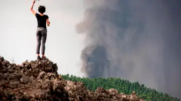 Una mujer observa la erupción de La Palma subida a una antigua colada volcánica en el municipio de El Paso. Una mujer observa la erupción de La Palma subida a una antigua colada volcánica en el municipio de El Paso.