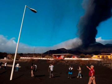 Una gruesa capa de ceniza y escoria cubre el techo de las viviendas del barrio de Las Manchas, en La Palma, y los terrenos adyacentes, dentro de la zona evacuada por su proximidad al volcán. En la imagen, los servicios de emergencia muestran a un grupo de periodistas los efectos de la erupción en la zona