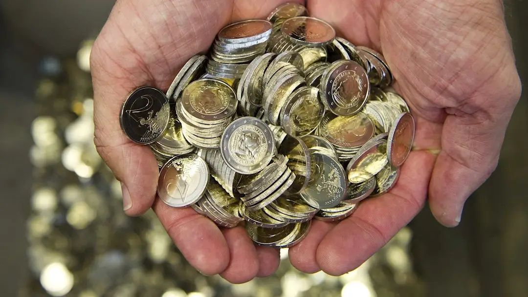 Un hombre sostiene varias monedas de euro, en una fotografía de archivo Un hombre sostiene varias monedas de euro, en una fotografía de archivo