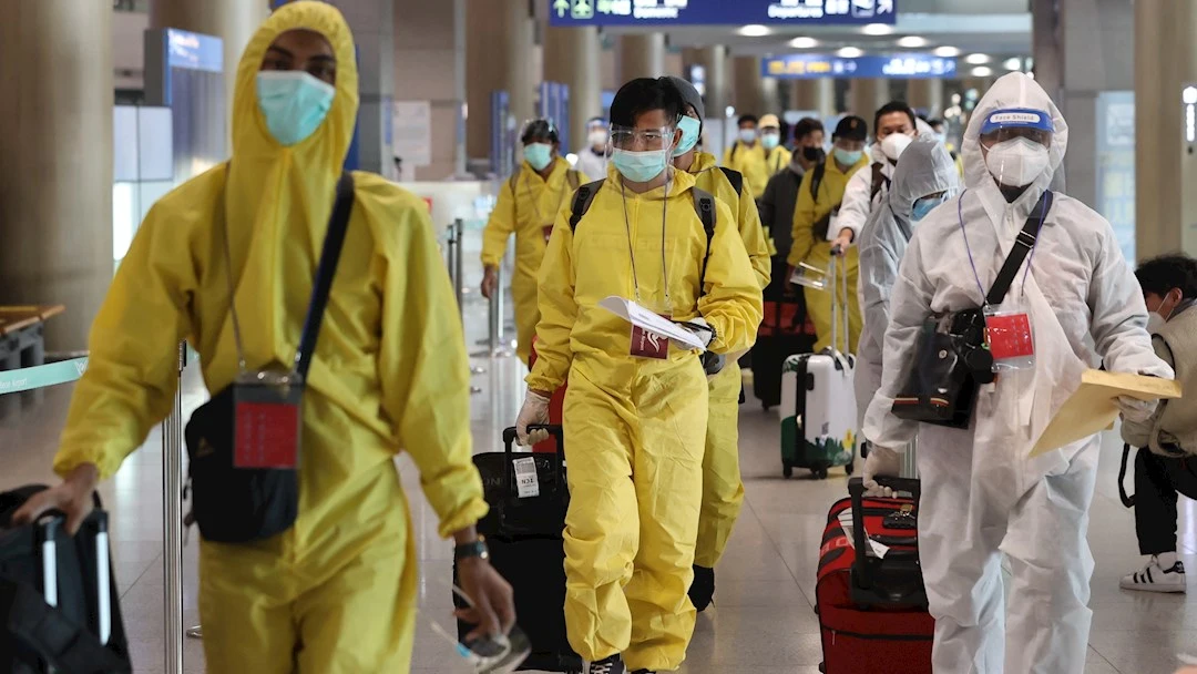 Varios viajeros con mascarilla en un aeropuerto Varios viajeros con mascarilla en un aeropuerto