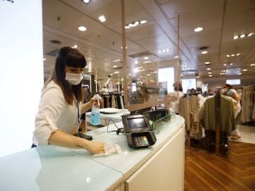 Una empleada desinfecta el mostrador de la tienda de un centro comercial, en una imagen de archivo