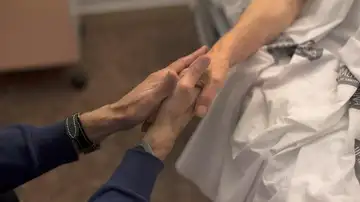 Una persona agarra la mano de un enfermo