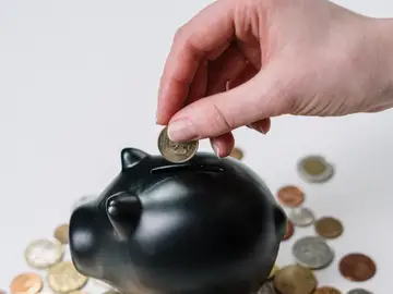 Imagen de una persona metiendo dinero en una hucha Imagen de una persona metiendo dinero en una hucha
