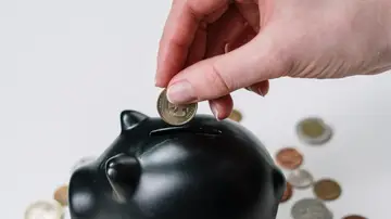 Imagen de una persona metiendo dinero en una hucha Imagen de una persona metiendo dinero en una hucha