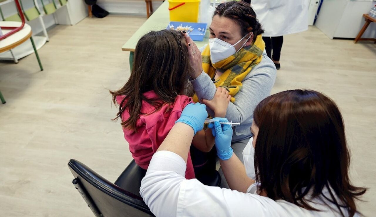 Una madre acompaña a su hija mientras la vacunan en el CEIP Blasco de Alagón de Vilafranca durante el inicio de la segunda fase de la campaña de vacunación pediátrica contra el coronavirus que comienza este jueves, centrada en los 186.088 niños y niñas de entre 8 y 5 años que estudian en los centros escolares de la Comunitat Valenciana.